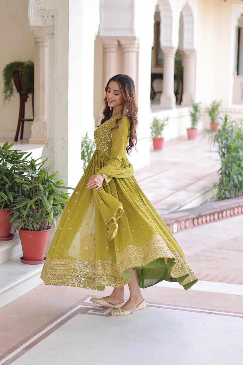 Woman in a yellow dress standing in a decorative outdoor setting with plants and architectural elements.